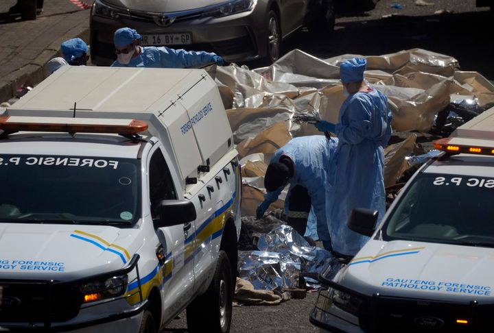 Forensic experts cover corpses at the scene of a deadly blaze in downtown Johannesburg, on Aug. 31, 2023.