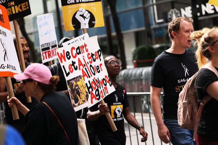 Members of WGAE and SAG-AFTRA hold signs while walking a picket line in solidarity with writers on children and family shows outside of NBCUniversal on Aug. 29 in New York City.