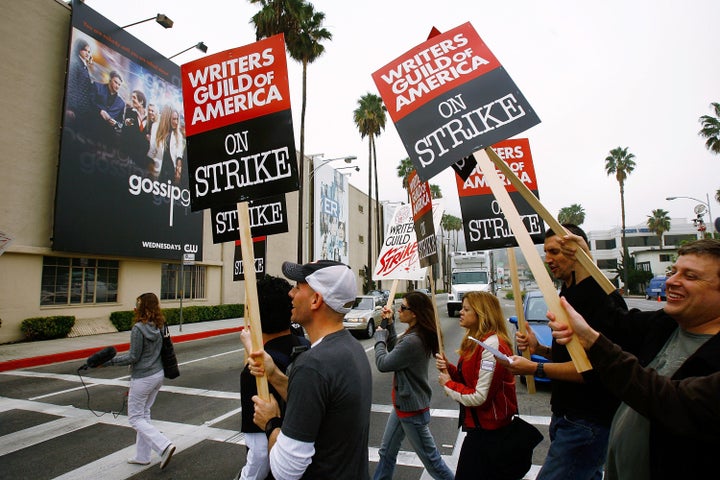 Writers walk up a picket line near a billboard for the television show "Gossip Girl" outside Warner Brothers Studios in November 2007.