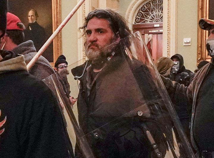 Dominic Pezzola, who broke into the US Capitol with a police sign, walks outside the Senate room with other rioters on January 6, 2021.