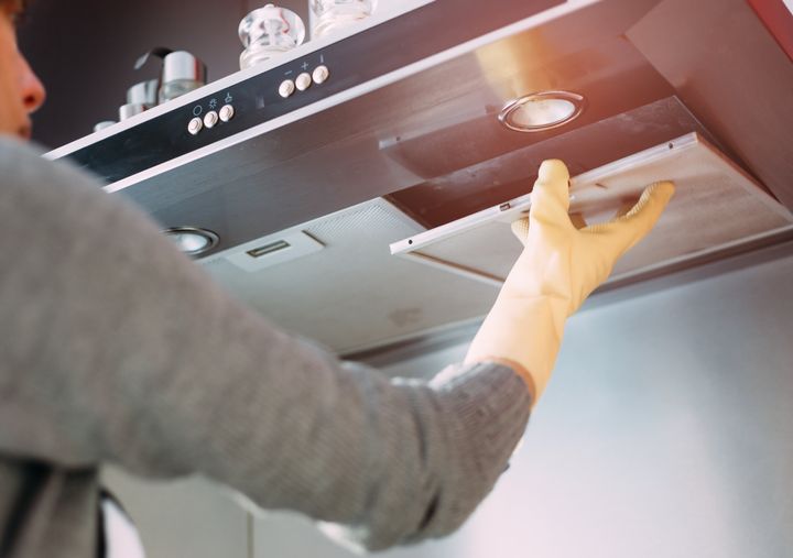 Close up of woman removing dirty filter from kitchen hood