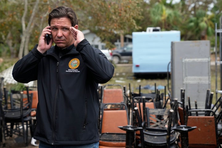 Florida Gov. Ron DeSantis talks on the phone with President Joe Biden as he stands outside storm-damaged restaurant Shrimp Boat during a visit to Horseshoe Beach, Fla., one day after the passage of Hurricane Idalia, Thursday, Aug. 31, 2023. (AP Photo/Rebecca Blackwell)