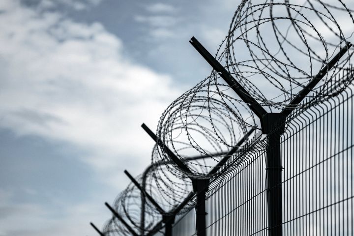 Barbed Wire Fence. Prison or border fence with razor wire against dark sky. Security concept