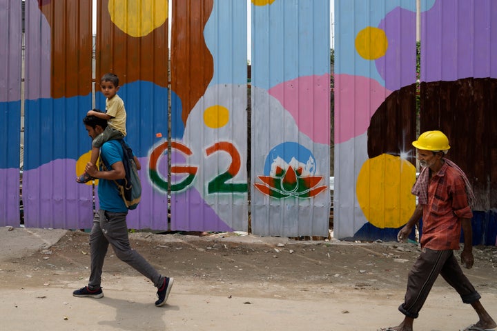 People walk past a construction site covered with G20 summit logo, in New Delhi, India, on Aug. 24, 2023.