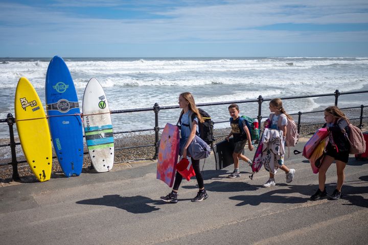 Visitors with body boards walk along the lower promenade at Saltburn beach. Beachgoers are avoiding the sea due to recent pollution alerts along the UK's North East as well as coastal regions countrywide. 