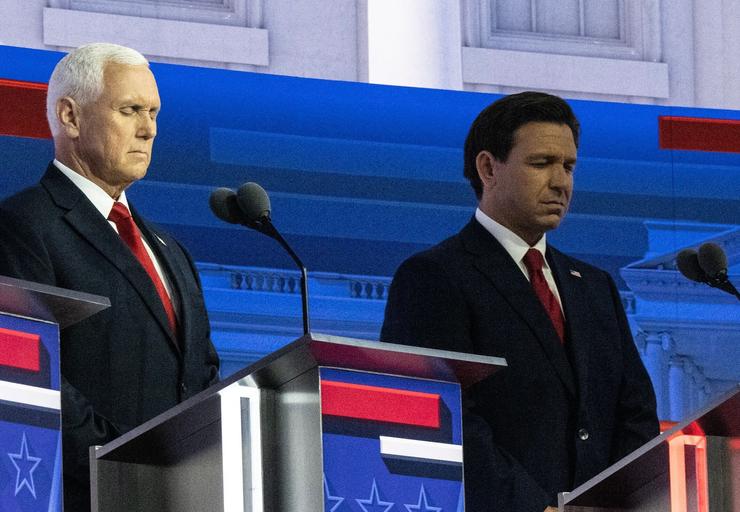 Former Vice President Mike Pence and Florida Gov. Ron DeSantis close their eyes during the first Republican presidential primary debate, Aug. 23, in Milwaukee.