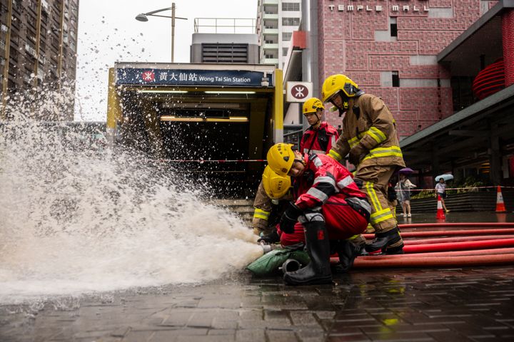 Fire-fighters drain out water outside a MTR station following heavy rainstorms in Hong Kong, on Sept. 8, 2023. 