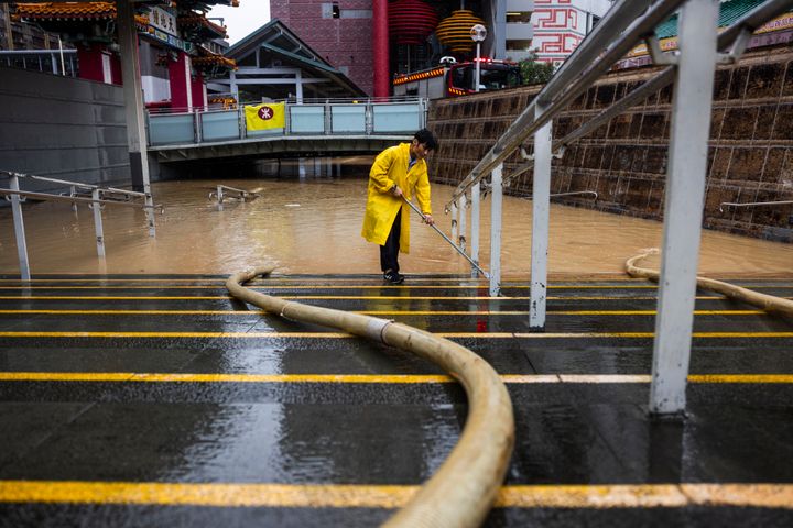 Seorang pekerja membersihkan air di jalan yang banjir setelah hujan badai lebat di Hong Kong, pada 8 September 2023.