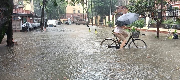 A citizen rides past standing water in a community after heavy rains in Nanjing, Jiangsu province, China, July 19, 2023.