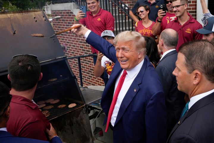 Former President Donald Trump holds a spatula with a hamburger on it as he works the grill during a stop at the Alpha Gamma Rho, agricultural fraternity, at Iowa State University before an NCAA college football game between Iowa State and Iowa, Saturday, Sept. 9, 2023, in Ames, Iowa. (AP Photo/Charlie Neibergall)