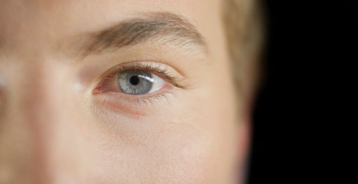 Close-up of man with grey eye looking into camera.