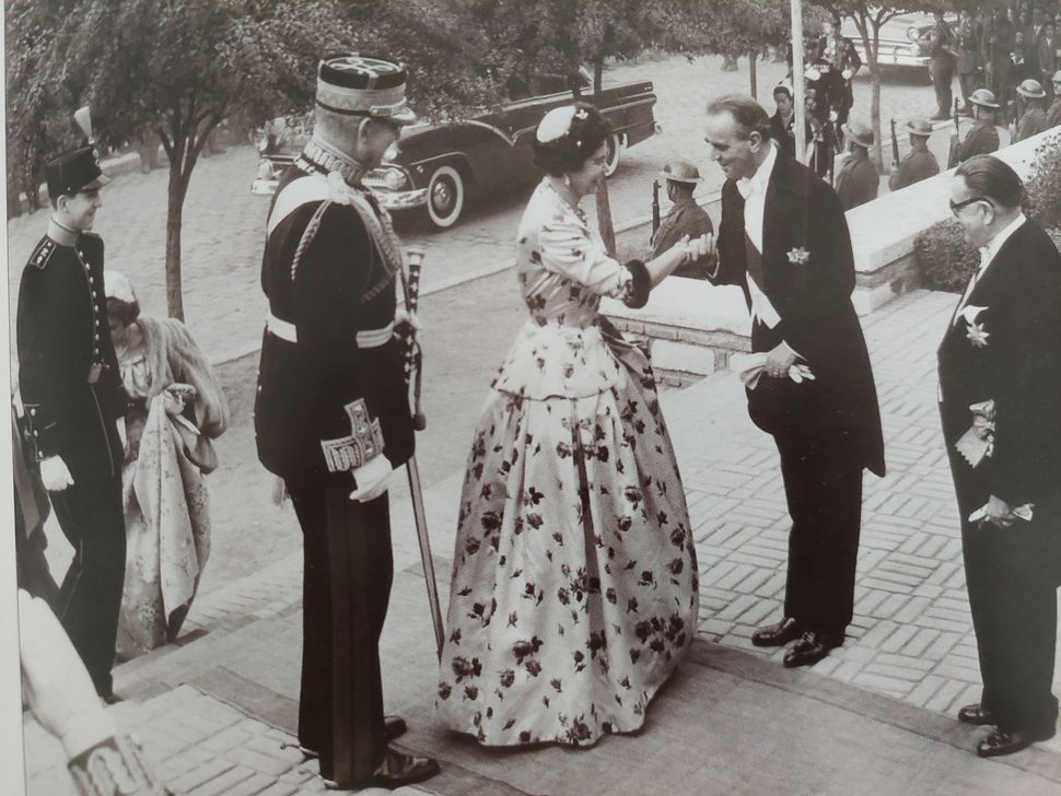 Η τότε βασίλισσα Φρειδερίκη σε επίσημη εμφάνιση με δημιουργία του οίκου Μαυρόπουλου. Δεξιά ο Κωνσταντίνος Καραμανλής, αριστερά ο τότε βασιλιάς, Παύλος. 