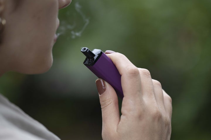 A woman smokes a vape cigarette in London.