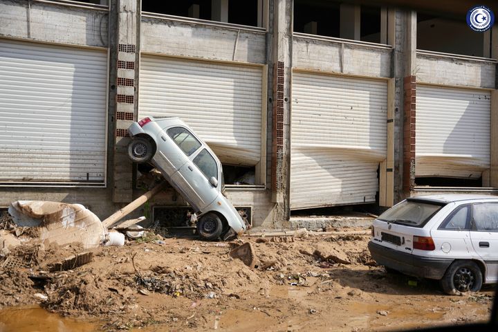 A car sits suspended against a shop front after being carried by floodwaters in Derna on Monday.