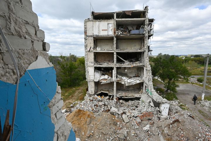 A person walks past a residential building destroyed as a result of hostilities in the town of Izyumin Ukraine.