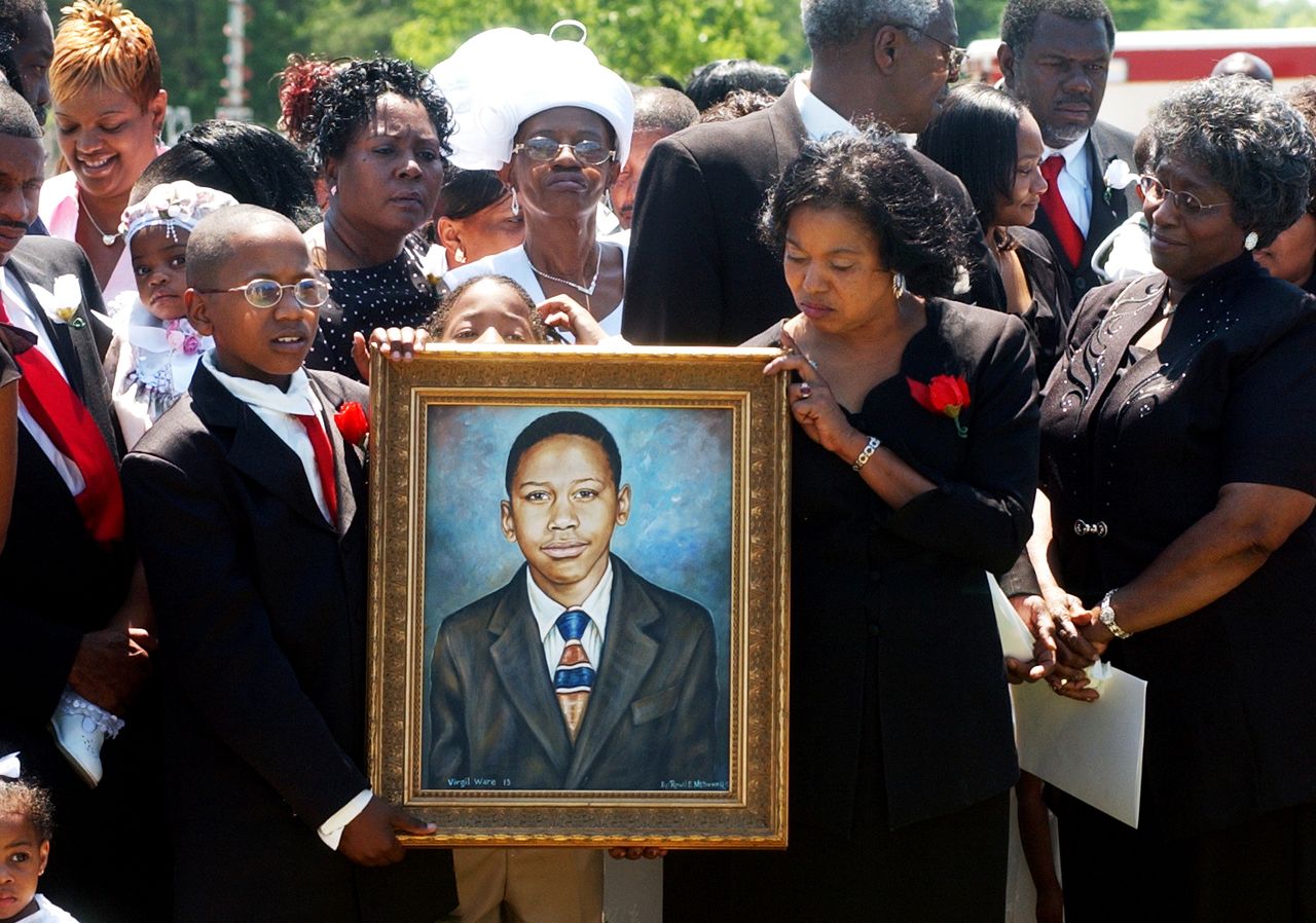 Donnell Jackson,13, left, and Shirley Floyd, right, hold up a portrait of Virgil Ware as members of Ware's family stand behind it during a memorial ceremony for Ware in Birmingham, Alabama, on May 6, 2004.