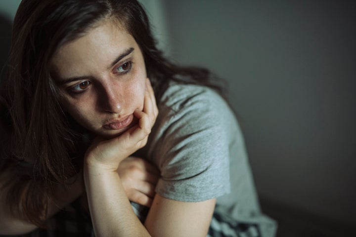 Close-up of sad, depressed woman sitting on the floor at home.