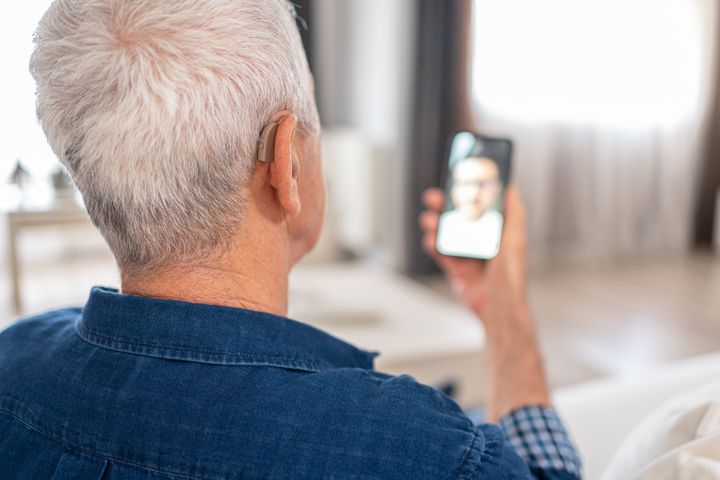 Senior Man With Hearing Aid Having Video Conference