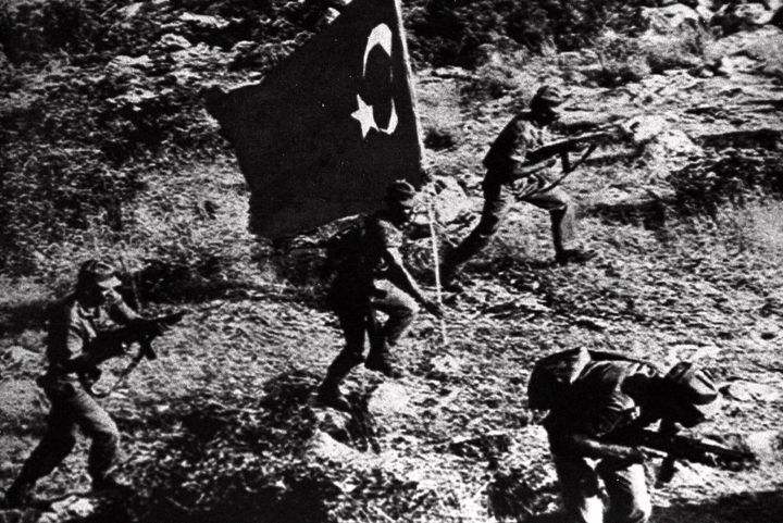 Carrying a Turkish flag, Turkish soldiers advance during the fighting that followed the July 20, 1974, Turkish invasion of Cyprus. (AP Photo)