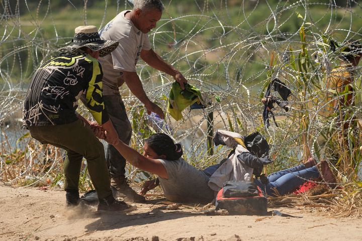 A migrant who crossed into the U.S. from Mexico is pulled under concertina wire along the Rio Grande on Thursday in Eagle Pass.