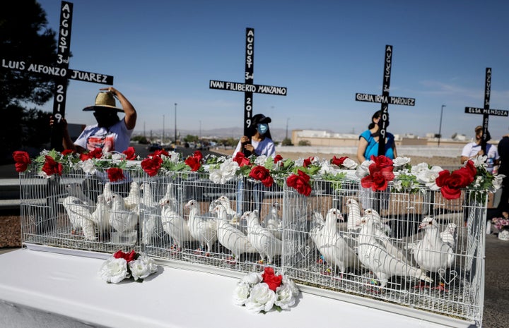 Twenty-three doves await release outside an El Paso Walmart as mourners hold crosses honoring those killed, one year after the 2019 attack.