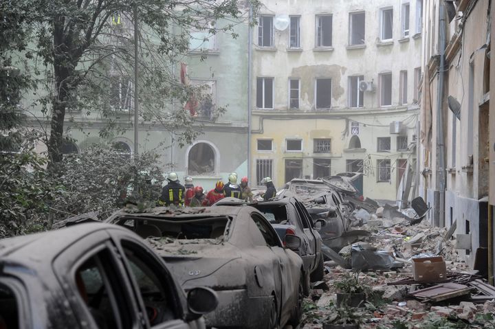 Emergency service workers gather outside damaged buildings as search for victims continues following a Russian missile attack in Lviv, Ukraine, in July.