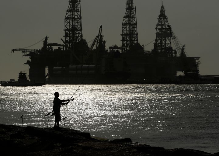 A man fishes near an oil drilling platform in May 2020, in Port Aransas, Texas.