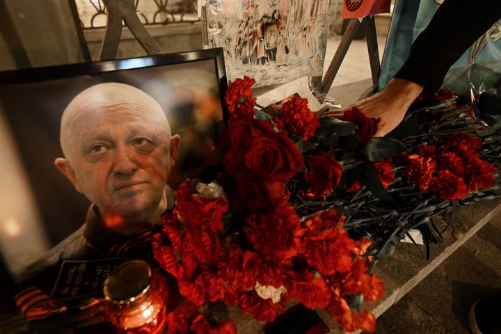 A man lays flowers at the makeshift memorial in honour of former Wagner boss Yevgeny Prigozhin.