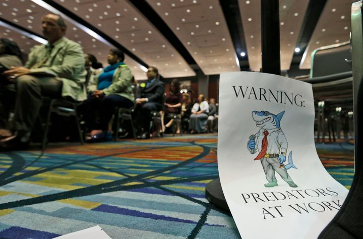 A sign warning of predatory payday lenders leans against a chair during a speech by then-CFPB Director Richard Cordray in 2015.