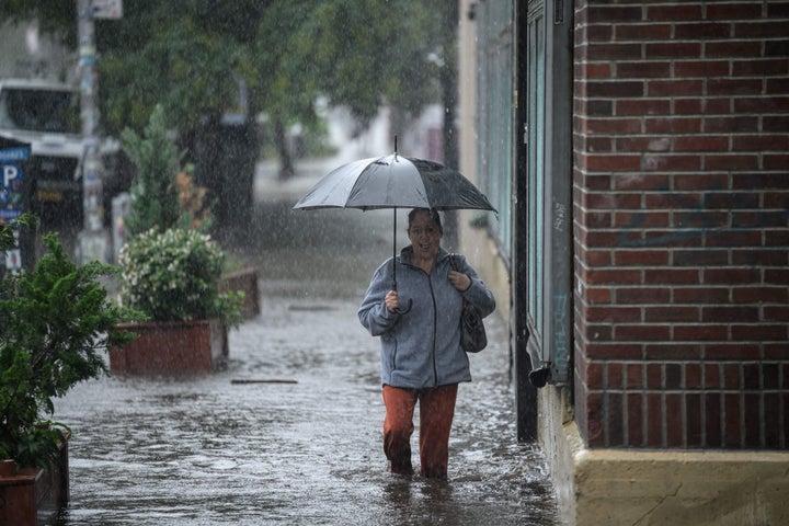 A woman holding an umbrella walks through through floodwater in Brooklyn, New York on September 29, 2023. (Photo by Ed JONES / AFP) (Photo by ED JONES/AFP via Getty Images)