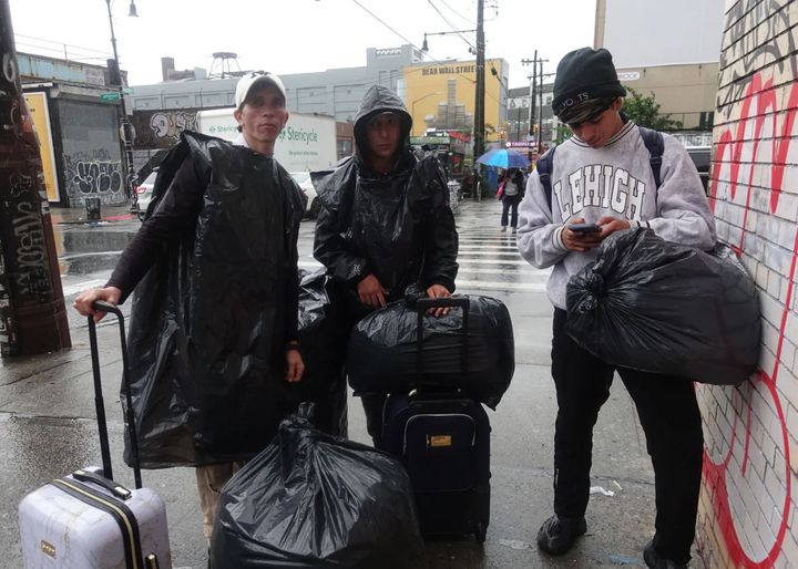 Migrants Victor Arana, left, Jose Leal and Argenes Cedeño outside the shelter, in the storm