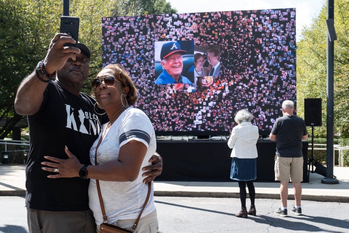 Kevin and Ursula Jones take a photo together in front of a video screen while attending the celebration for former President Jimmy Carter's 99th birthday held at The Carter Center on Saturday. (AP Photo/Ben Gray)