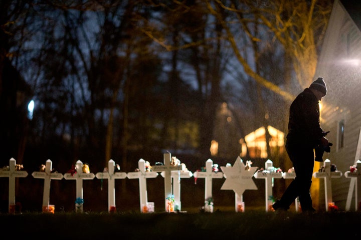 Frank Kulick, walks past a display of wooden crosses, and a Jewish Star of David, representing the victims of the Sandy Hook Elementary School shooting, on his front lawn, Monday, Dec. 17, 2012, in Newtown, Conn. (AP Photo/David Goldman)