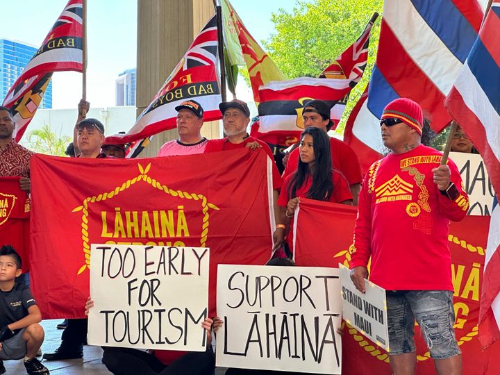 Lahaina residents and their supporters hold signs and flags at the Hawaii State Capitol in Honolulu on Oct. 3, 2023, at a news conference about a petition asking Hawaii Gov. Josh Green to delay plans to reopen a portion of West Maui to tourism starting this weekend. 