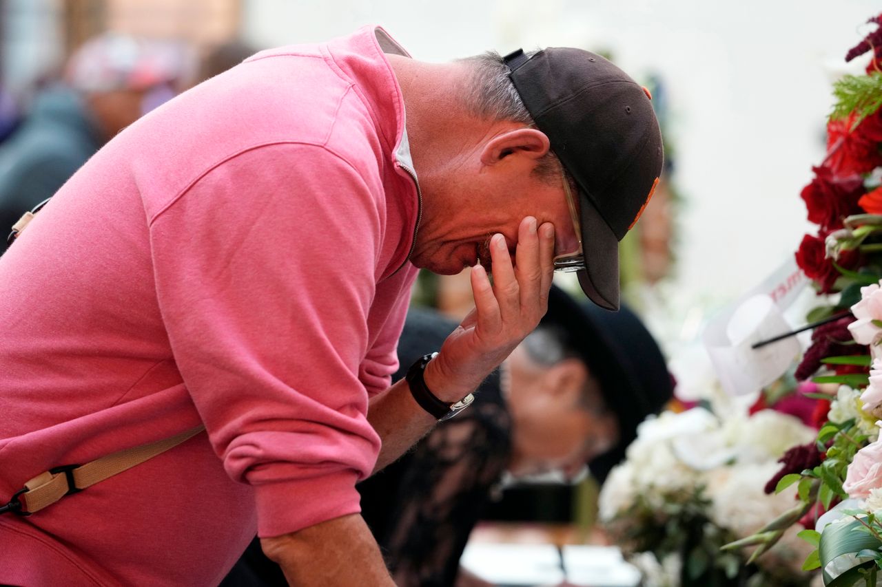 Mourner Rand Salwasser wipes tears from his face as he writes a message for Feinstein at City Hall. 