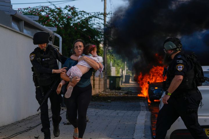 イスラエル南部の街アシュケロンで、子どもを抱く市民を避難させるイスラエルの警察（2023年10月7日）