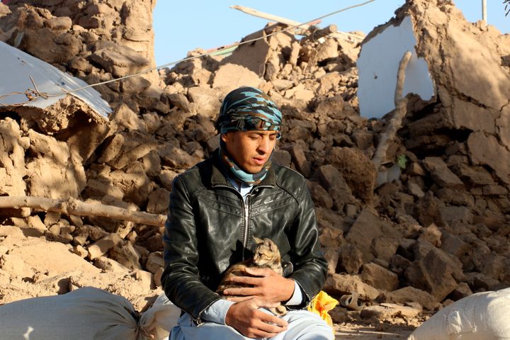 地震により倒壊した自宅の中庭で、猫を抱いているアフガニスタンの少年＝10月8日