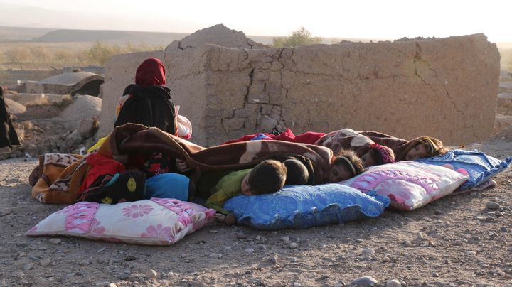 被害を受けた家屋のそばで毛布の下で休むアフガニスタンの子どもたち＝10月7日