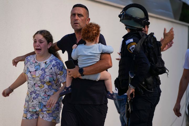 攻撃を受けたイスラエル南部のアシュケロンで、イスラエル警察に避難誘導される家族（10月7日）