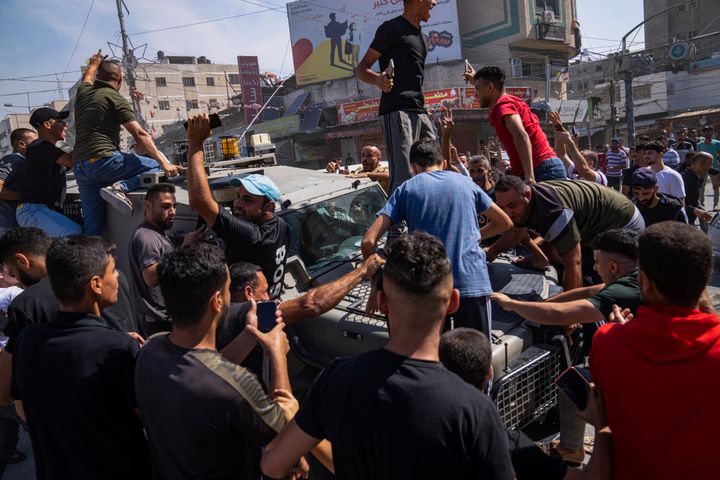 ガザ地区のシュジャイヤで、パレスチナの部隊によって持ち込まれたイスラエルの軍車両を取り囲むパレスチナの市民（10月7日）