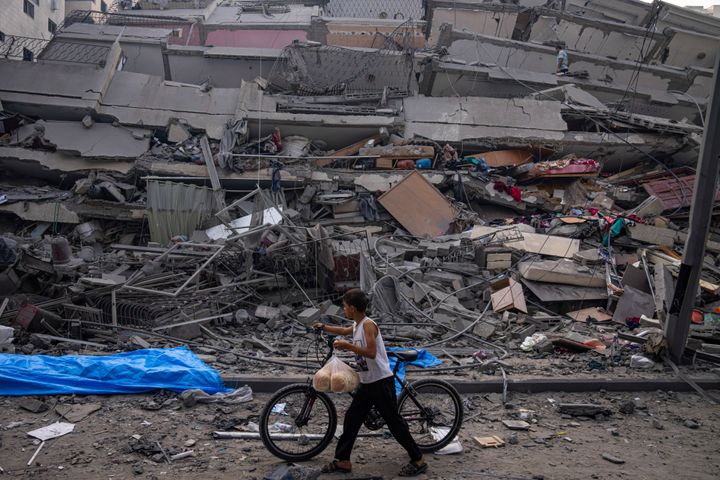 イスラエルによるガザ地区空爆によって破壊された建物の脇を自転車で通るパレスチナの子供（10月8日）