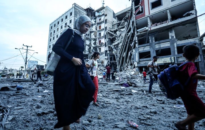 イスラエルによるガザ地区空爆によって破壊された建物の脇を通るパレスチナ市民（10月8日）