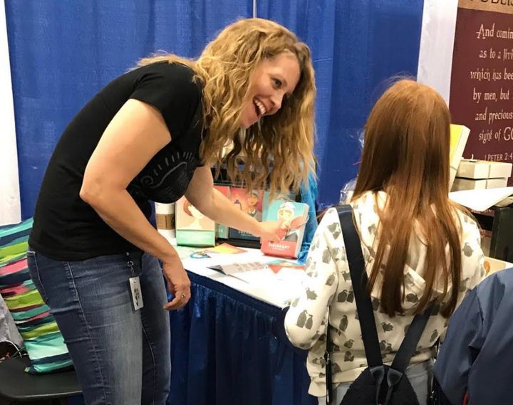 The author discussing the stories of historical women with an intrigued customer at a homeschool conference in Texas.
