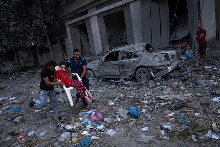Παλαιστίνιοι στην Λωρίδα της Γάζας μεταφέρουν στα χέρια με καρέκλα νεαρή γυναίκα εν μέσω των σφοδρών βομβαρδισμών του Ισραήλ (10 Οκτωβρίου 2023)