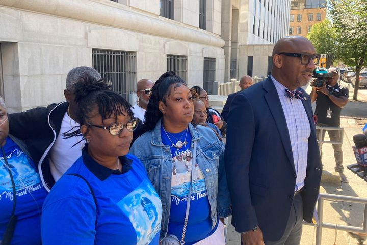 Attorney Mawuli Davis, right, speaks to reporters on Monday, Oct. 9, 2023, outside the Fulton County courthouse in Atlanta, while flanked by relatives of Johnny Holman Sr. 