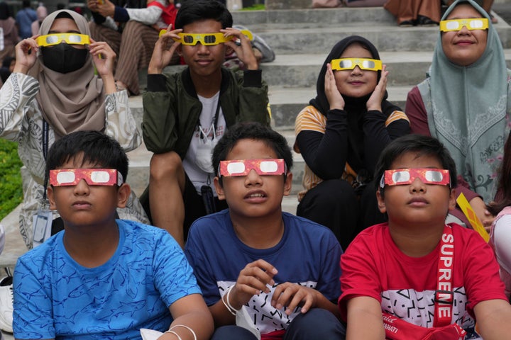 Youths wear protective glasses to watch a hybrid solar eclipse in Jakarta, Indonesia in April. On Saturday, Oct. 14, 2023, an annular solar eclipse -- better known as a ring of fire -- will briefly dim the skies over parts of the western U.S. and Central and South America.