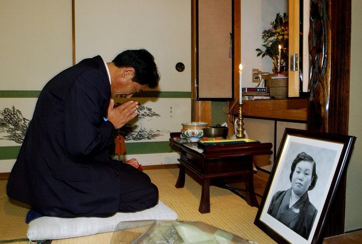 北朝鮮から24年ぶりに帰郷し、我が家で亡き母親の登志子さんの遺影が飾られた仏壇に手を合わせ帰国を報告する地村保志さん＝2002年10月17日、福井県小浜町（代表撮影）