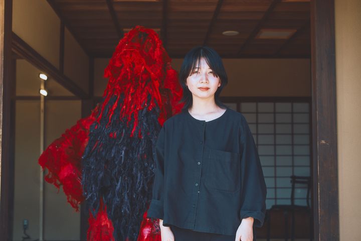 デニムの廃材などを加工した赤い襤褸のドレスを制作したデザイナーの八木華さん。津野青嵐さんと同じく「coconogacco（ここのがっこう）」で学び、2019年、ITSのファイナリストに最年少19歳で選出された。