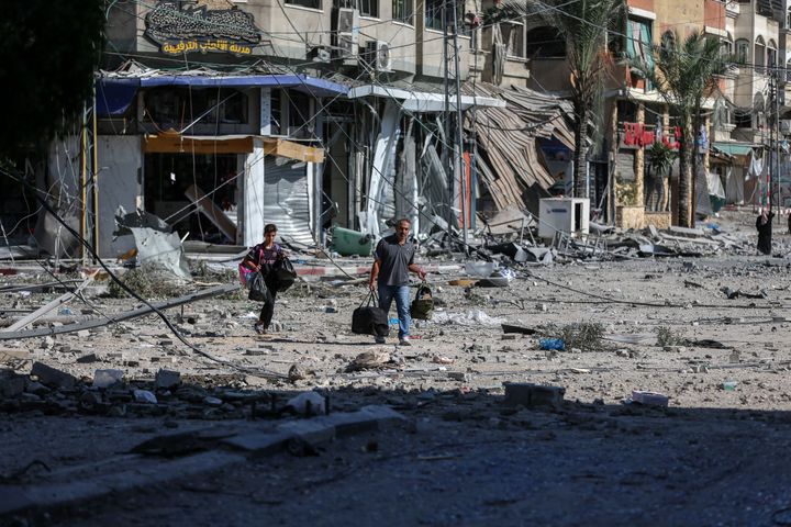 Orang-orang berjalan di tengah kehancuran rumah dan jalan di Khan Yunis, yang terletak di Jalur Gaza selatan, di tengah kehancuran akibat serangan udara Israel. 