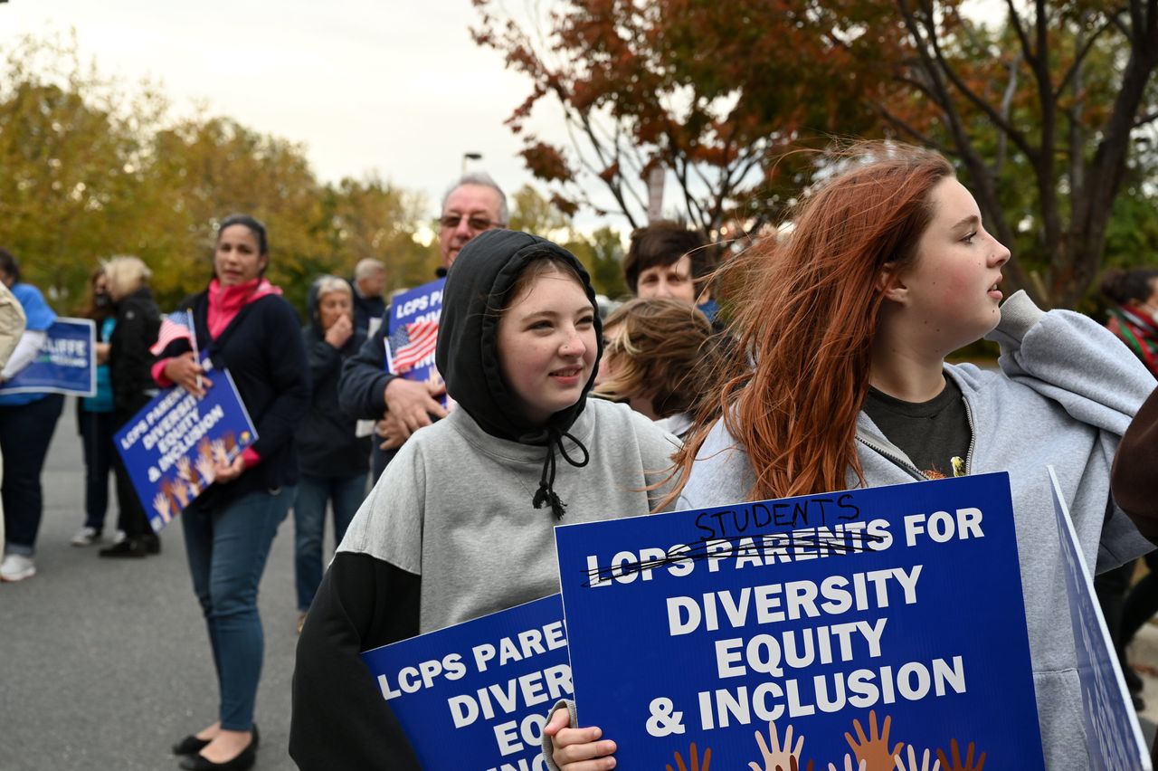 Students, parents and others hold signs outside the Loudoun County school board meeting Oct. 26, 2021, in Ashburn.